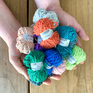Eco-Bonbons in Nurturing Fibres Eco-Fusion, assorted colors, arranged on the palms of someone's hands